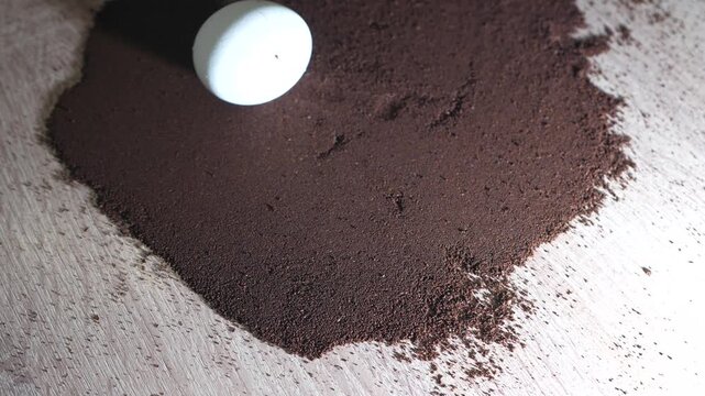 Boiled egg resting on ground coffee in a minimal creative food composition, showing an unusual breakfast concept and conceptual still life