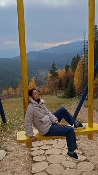 Swinging in the mountains with fall colors all around and a view of the hills in the distance