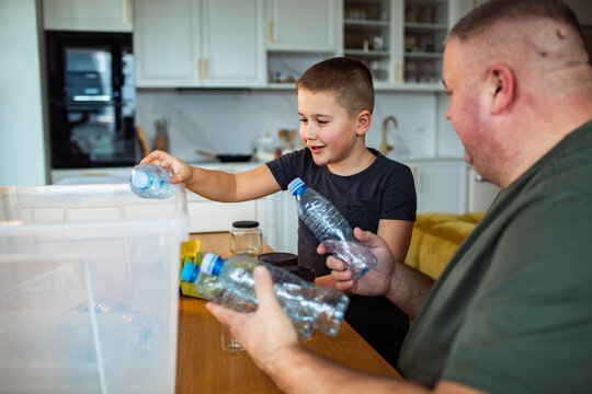 Parent and child recycling plastic bottles in kitchen