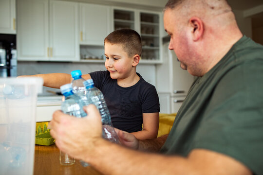 Man and boy packing water bottles in kitchen