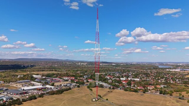 Aerial view of the Lakihegy radio mast, a historic broadcast transmitter above dry fields, industrial buildings and suburban homes in Szigetszentmikl&oacute;s, Hungary.
