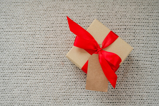 Christmas gift box with a red ribbon on a cozy knitted blanket