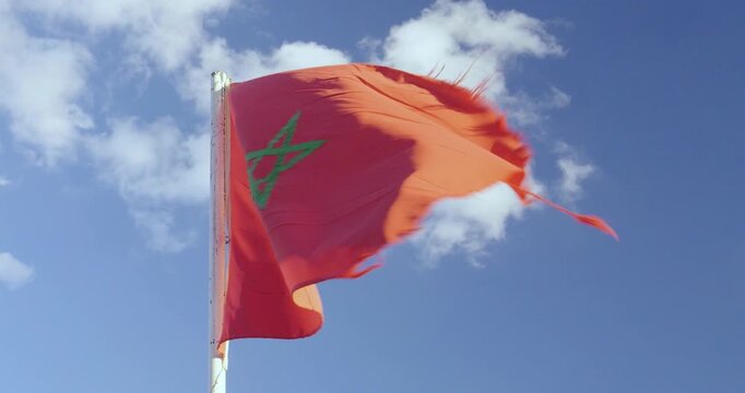 Moroccan National Flag Waving in the Wind Against a Blue Sky with White Clouds