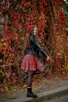 student girl in red beret turning around against red autumn leaves wall