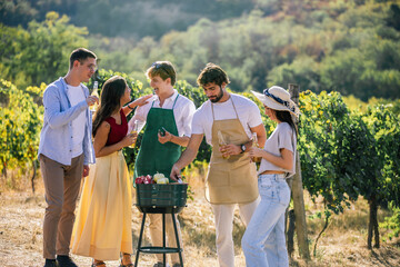 Naklejka premium Friends walking together through a vineyard during an outdoor food gathering