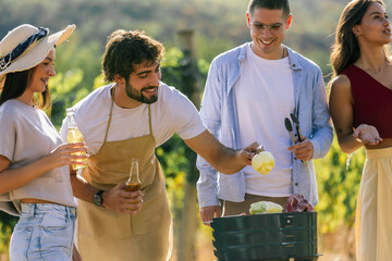 Naklejka premium Friends cooking together and sharing drinks in a sunny vineyard