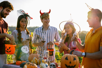 Naklejka premium Friends in Halloween costumes enjoying drinks at a vineyard party