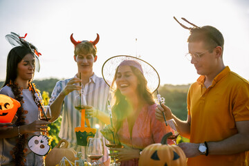 Naklejka premium Friends celebrating Halloween together with drinks at an outdoor vineyard party