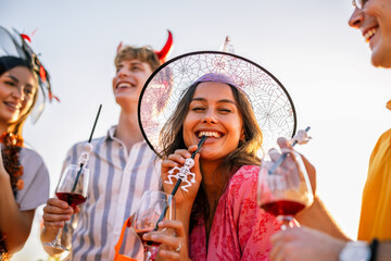Naklejka premium Woman in Halloween witch costume smiling among friends outdoors