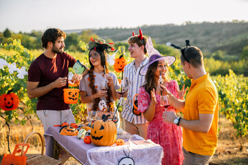 Naklejka premium Friends in colorful Halloween costumes celebrating in a vineyard