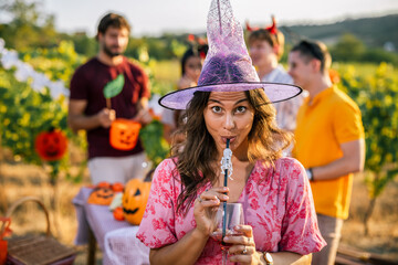 Naklejka premium Woman in witch costume holding a drink at a Halloween vineyard party