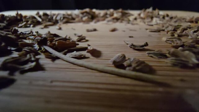Macro shot of dry carrot seeds spread on a wooden board surface, ideal for agriculture and gardening themes.   