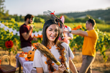 Naklejka premium Woman in Halloween costume smiling with friends at a vineyard party