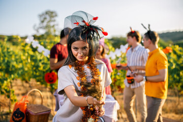 Naklejka premium Woman carrying a broom while celebrating Halloween with friends in a vineyard