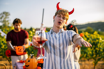 Naklejka premium Man wearing devil horns reaching toward the camera at a Halloween party