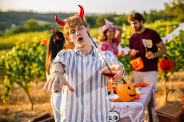 Naklejka premium Man in devil horn costume gesturing during a Halloween vineyard celebration