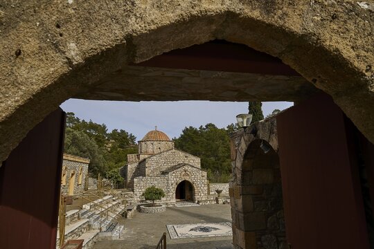 View through a stone arch onto a church surrounded by trees, monastery, Moni Thari, near Gadouras reservoir, lonely mountain region, Rhodes, Dodecanese, Greek Islands, Greece