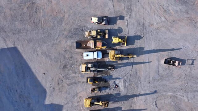 Aerial view of heavy construction machinery including excavators and dump trucks parked in a row on a construction site in Buffalo, New York, United States.