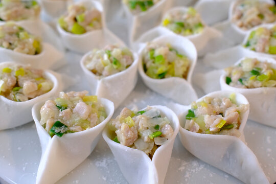 Asian kitchen. Artistic arrangement of open-topped dumplings with pork filling on white plate.
