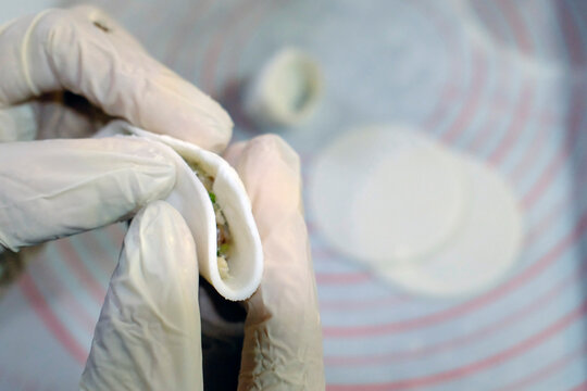 A close-up view of a hand filling a dumpling wrapper with a flavorful mix of ingredients, showcasing the artisanal process of making traditional dumplings. Asian kitchen.