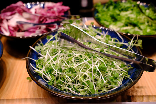 Three bowls of fresh greens including microgreens and shredded vegetables for garnish. Vietnam.