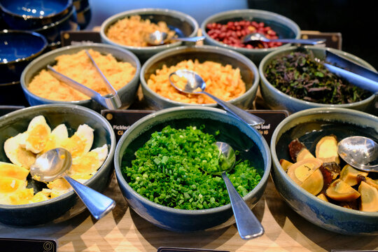 Restaurant condiment station with herbs, pickled vegetables, and garnishes for noodle soup. Vietnam.