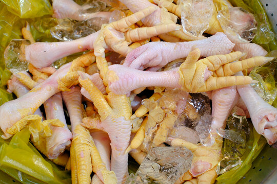 Fresh uncooked chicken feet stored on crushed ice at a wet market stall. Vietnam.