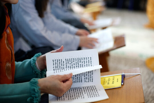 Tu An pagoda. Hands of devotees holding Vietnamese Buddhist sutra sheets during a communal prayer ceremony. France.