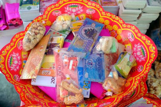 VRed lotus tray filled with votive paper money, snacks and miniature goods for ancestor offerings. Ho Chi Minh city. Vietnam.