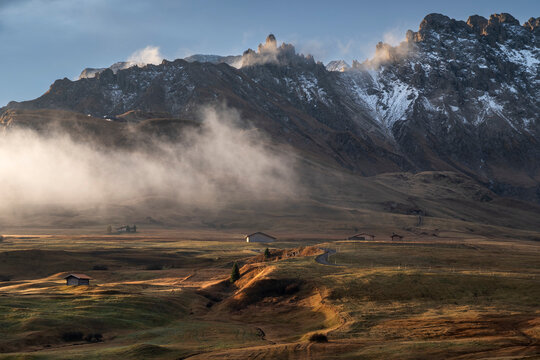 Alpine Huts and atmospheric conditions below the Schillar Range at first light, Alpe di Siusi or Seiser Alm high Alpine meadow, The Dolomites, South Tyrol, Italy