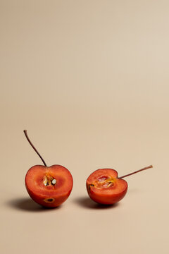 Two Halved Red Crab Apples on Beige Background with Copy Space
