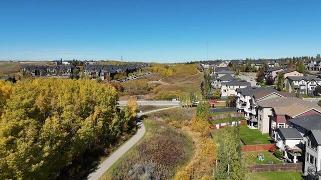 Aerial view of suburban houses in autumn along colourful ravines. 