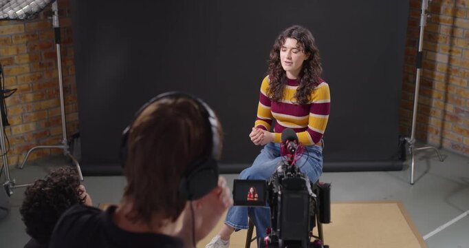 Female talent responding to operator cue and speaking in studio while operator adjusting camera