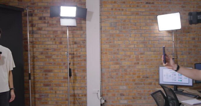 Diverse crew cueing presenter and capturing his monologue in studio with camera, phone, lav mic