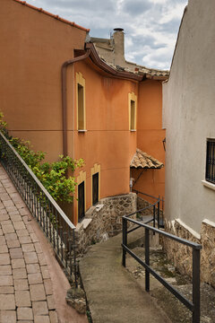 Traditional village street with stairway, railings, stone walls and orange house facades in Zorita de los Canes, Guadalajara, Castilla-La Mancha, Spain.