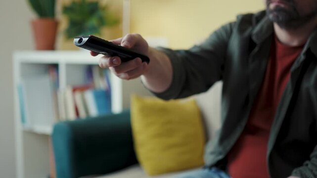 Male hands using electronics controller pointing toward camera in living room