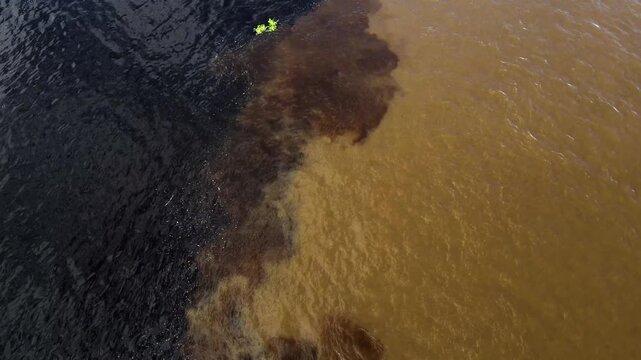 Aerial view of the confluence of the dark Rio Negro and sandy Solimoes River in Manaus, Amazonas, Brazil.