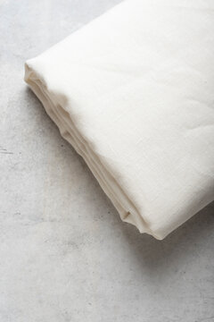 Folded Off White Linen Fabric on Concrete Surface