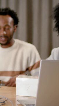 Vertical video: Reacting curly cohost in gray top speaking after host prompt at home, laptop-mic