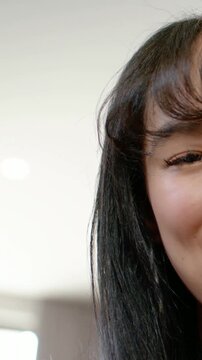 Vertical video: Smiling woman leaning in as camera moves at home, reacting to voice in orange knit