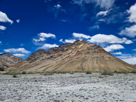 View of the rugged mountain landscape along the Penzi La road with arid slopes and rocky terrain under a bright blue sky in Zanskar, Ladakh, India.
