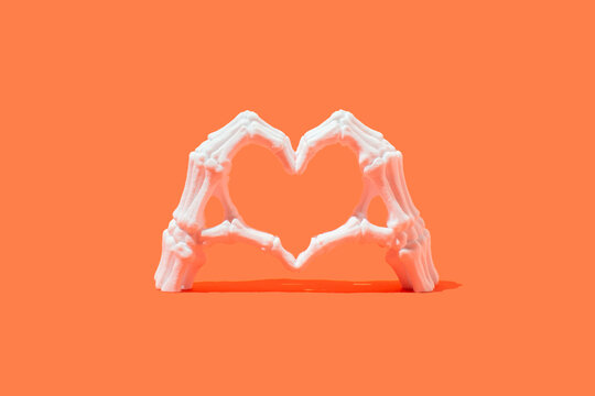 Skeletal hand in the heart shape on a orange background. 