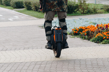 young man moving along sidewalk on unicycle in city park on embankment, unusual type of transport © Anton Pentegov