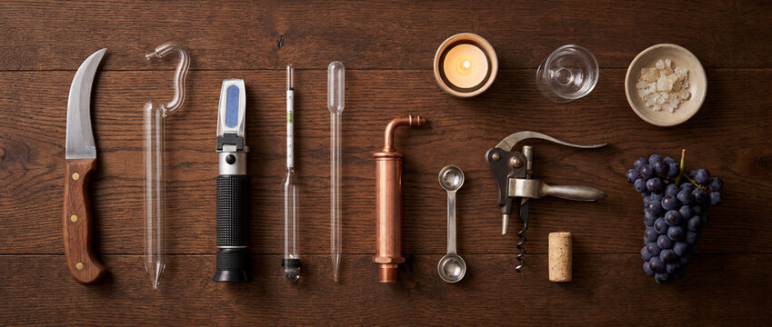 Winemaking tools and equipment layout with grapes corkscrew hydrometer refractometer knife and measuring spoons
