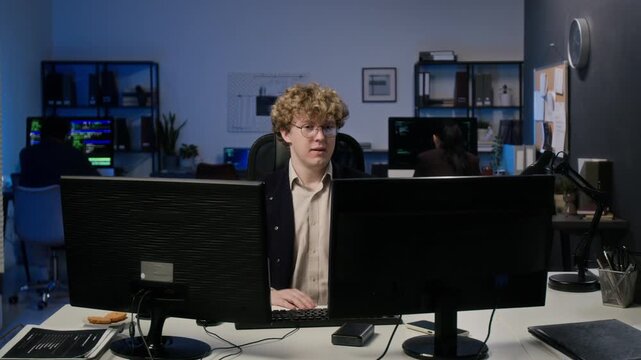 Caucasian young adult man finishing coding, leaning back with hands behind head and smiling. Useful for tech promo or corporate cybersecurity campaigns