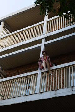 A mannequin of a girl sitting on the railing of a high-rise building