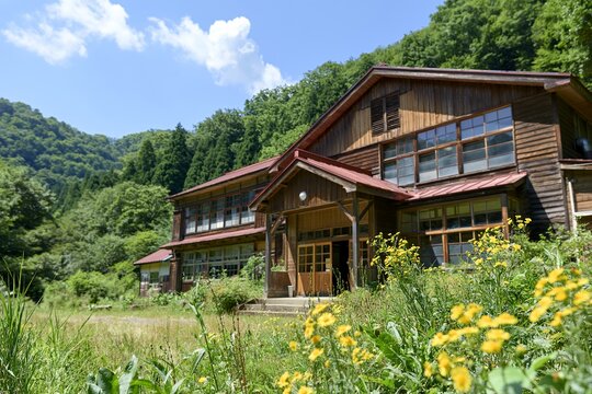 夏の里山で青空と野花に囲まれひっそり佇む懐かしい廃校