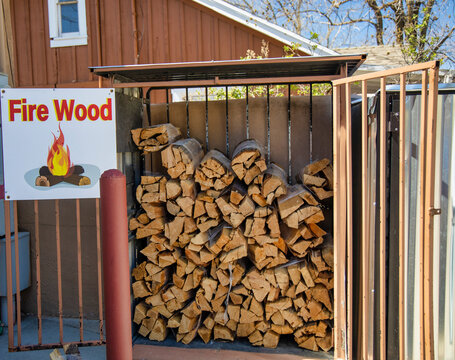 Fire wood bundles stacked in Outdoor Metal Caged Rack and fire wood sign on the side.