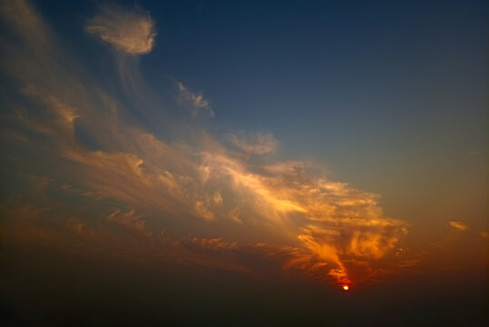 View of golden sunset clouds illuminated by the setting sun in the sky over Jahanian, Punjab, Pakistan.