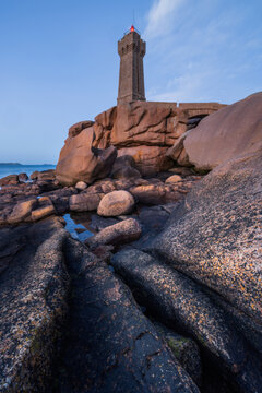 View of the Mean Ruz lighthouse standing on the iconic pink granite rocks of the Ploumanac'h coast in Perros-Guirec, Brittany, France.